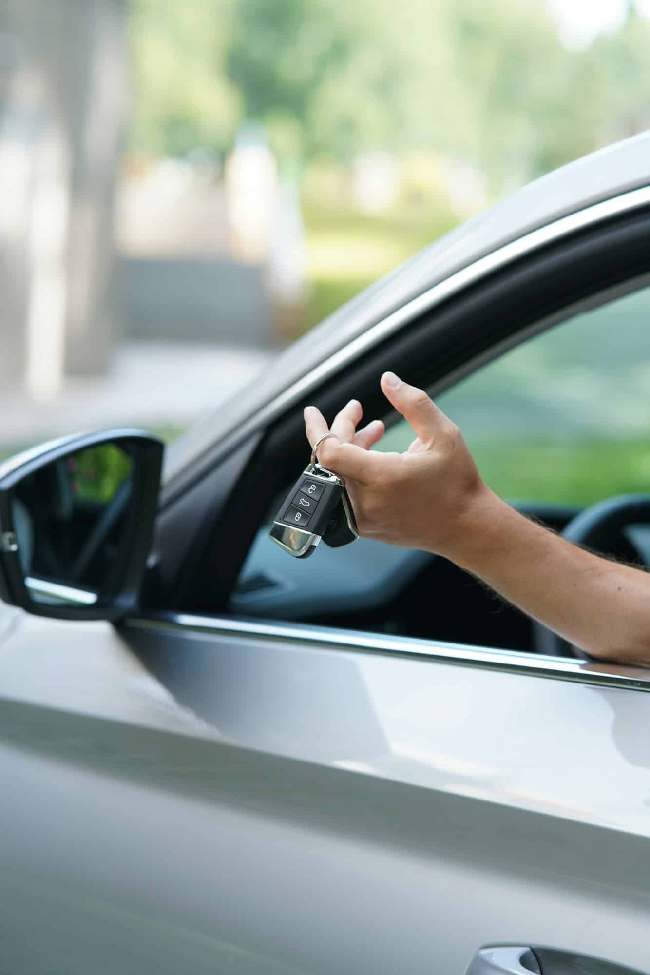 Man driver holding car keys of new car sitting inside. Excited to go on trip. Buying new car